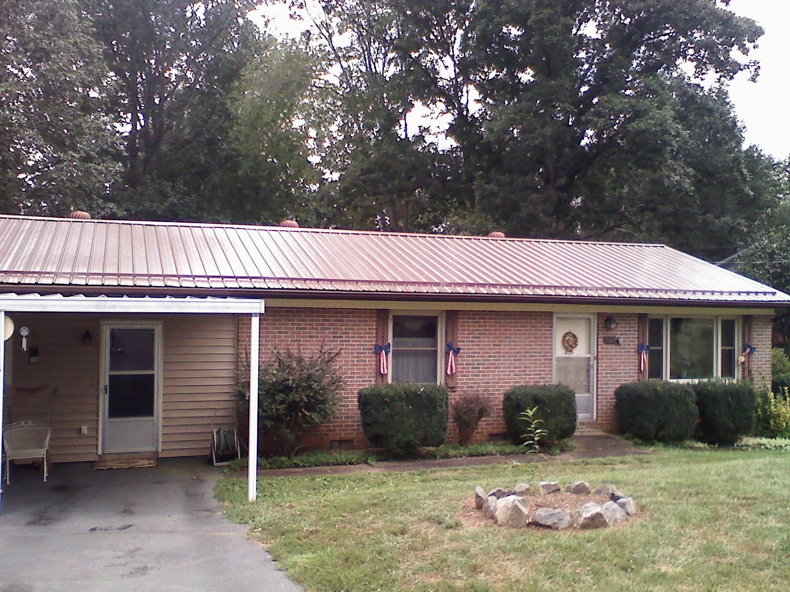 Bronze metal roof and carport on a brick ranch home — Roof Repair work by our crew in Osage